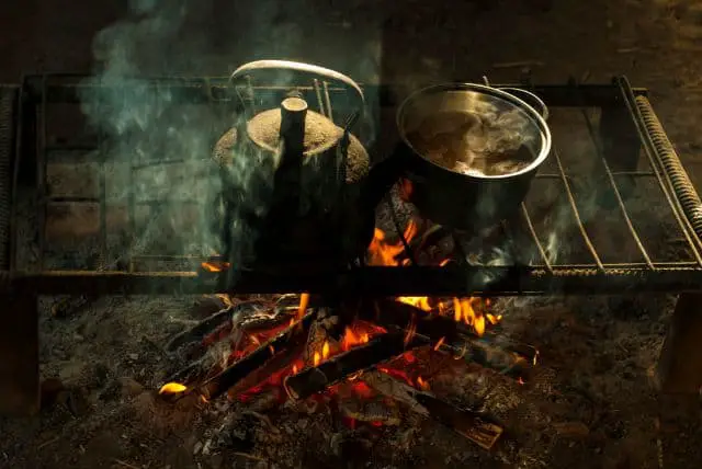 A kettle and pot of food cooking on a campfire on a primitive camping trip
