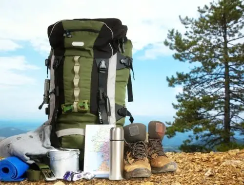 Hiking boots, backpack, and other camping gear on top of a mountain
